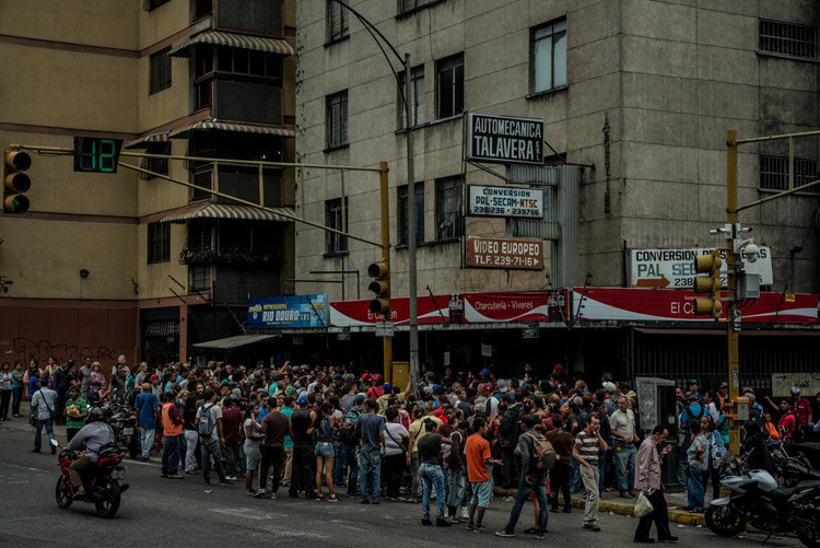 Người dân Venezuela xếp hàng từ nửa đêm trước một cửa hàng thực phẩm. Ảnh: Meridith Kohut/The New York Times