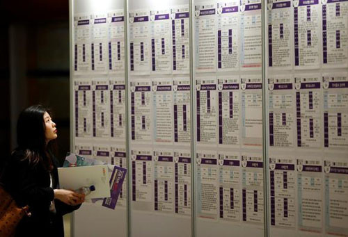Một phụ nữ Hàn Quốc đọc bảng tuyển dụng tại một hội chợ việc làm ở Seoul. Ảnh Reuters.