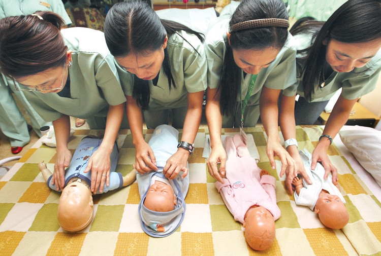 Phụ nữ Philippines thực hành chăm sóc trẻ với búp bê sơ sinh trong một lớp hộ sinh ở Manila. Với blockchain, họ có thể gởi tiền về nhà với chi phí không bằng một nửa so với gửi qua Western Union.