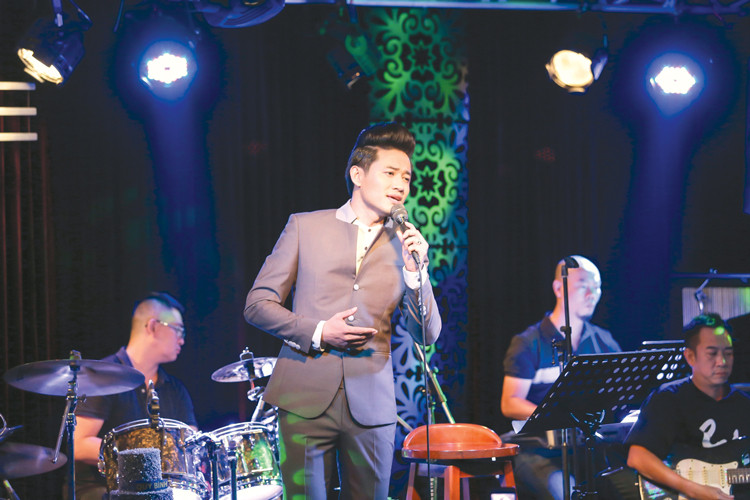 Diễn viên Quý Bình hát trên sân khấu một phòng trà