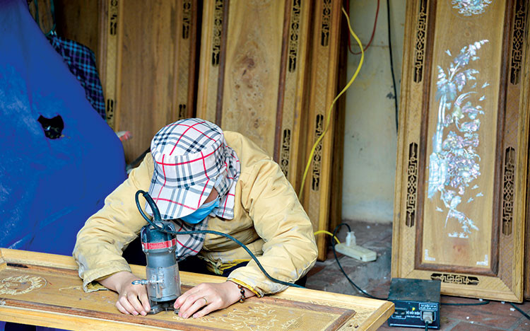 Thợ nghề của làng Chuôn Ngọ đang thực hiện chạm khảm xà cừ lên nền gỗ
