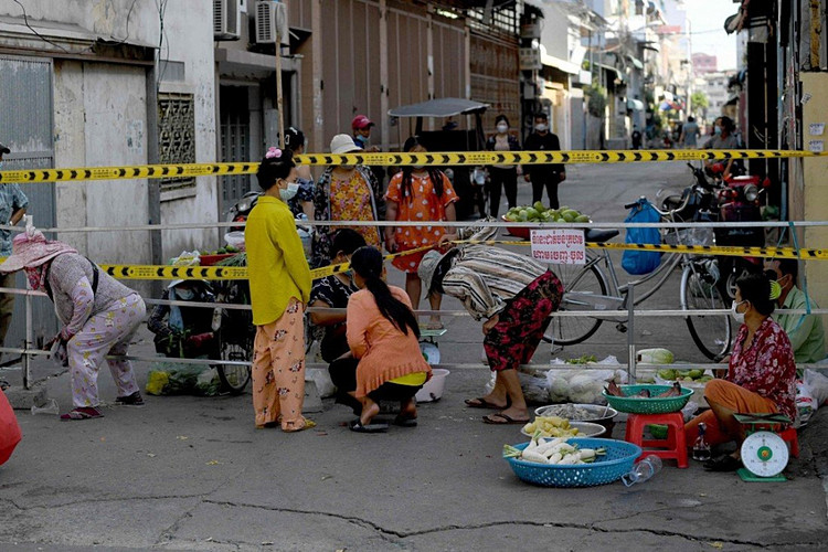 Người dân Phnom Penh nhóm chợ sát hàng rào cách ly một khu vực có nguy cơ lây nhiễm cao ngày 25/4/2021. Ảnh: AFP