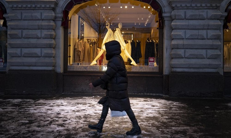 Người phụ nữ bước qua cửa sổ trưng bày tại một cửa hàng ở Quảng trường Đỏ, thủ đô Moskva, Nga ngày 28/3. Ảnh: AP.