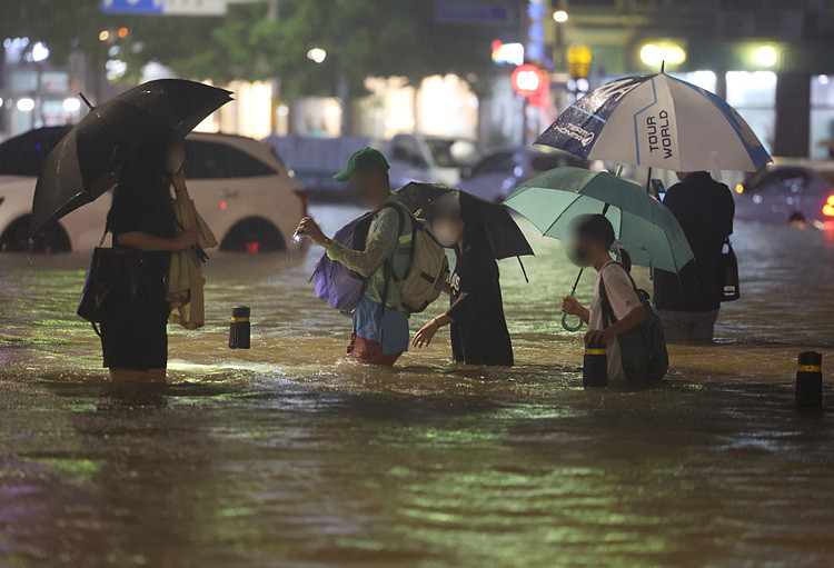 Người dân lội qua khu vực ngập nước ở quận Gangnam, Seoul trong trận mưa lịch sử hôm 8/8. Ảnh: Yonhap.