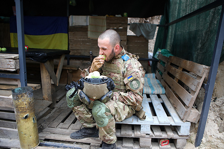 Một binh sĩ Ukraine ăn táo tại tuyến phòng thủ bên ngoài Kharkov ngày 3/8. Ảnh: AFP.