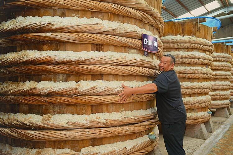 Ông Matsuo “lọt thỏm” giữa những thùng nước mắm cao khoảng 2.6m và rộng gần 3m, mỗi thùng chứa từ 12-15 tấn cá, được làm thủ công từ gỗ tự nhiên như gỗ bời lời, dên dên, hậu phát, bằng lăng…