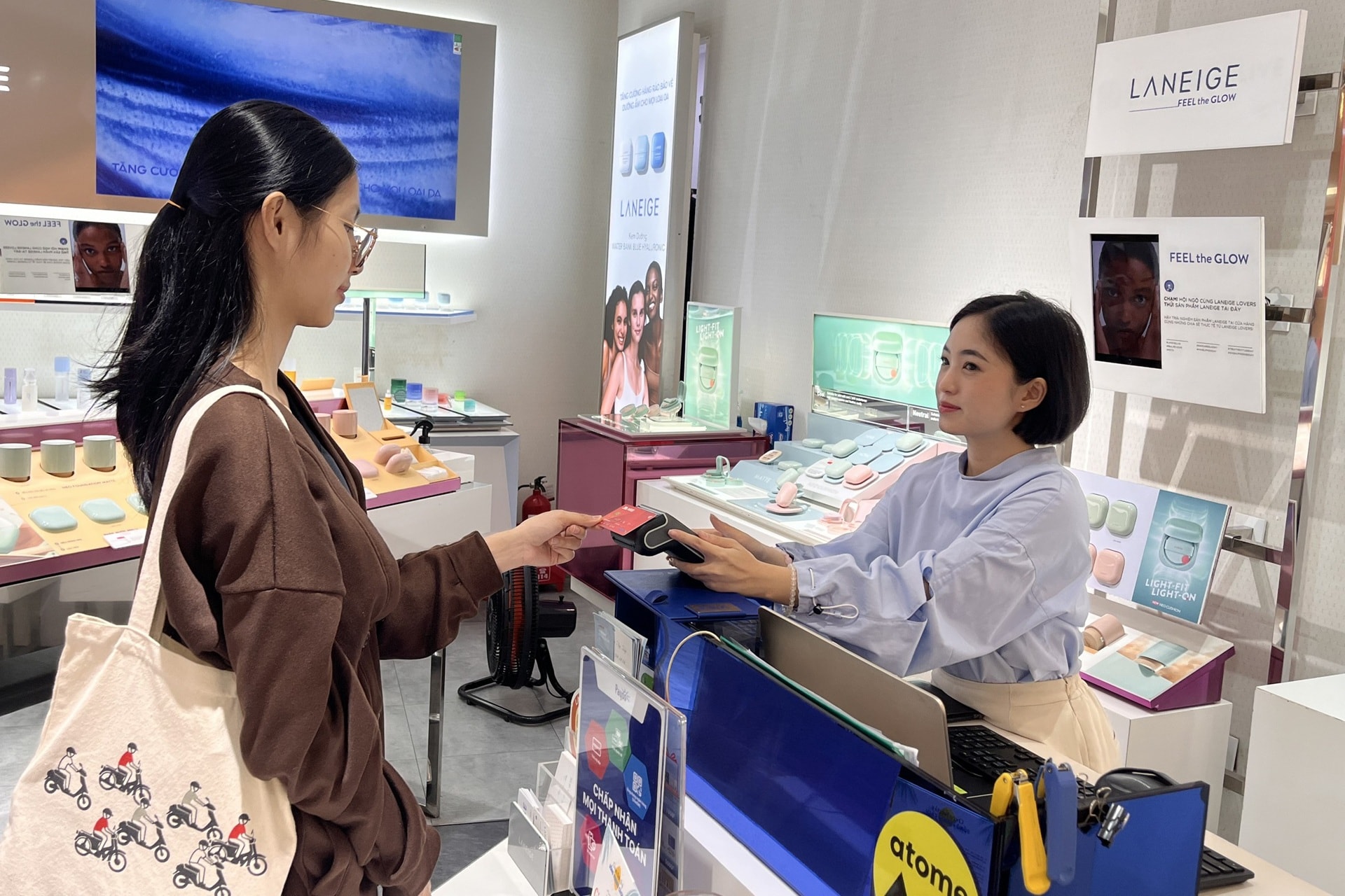 Khách hàng thanh toán chạm thẻ trên máy POS Payoo